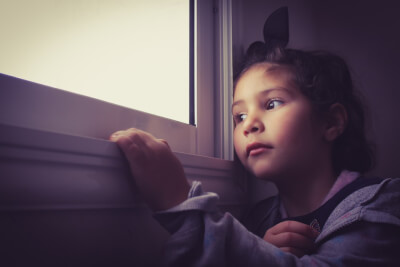 Picture of worried child looking out of a window